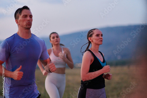A diverse group of runners trains together at sunset.