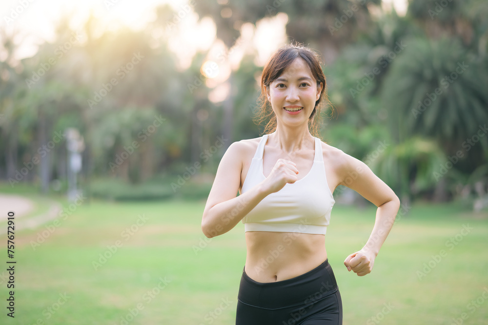 pretty asian woman jogger running in green nature public park.