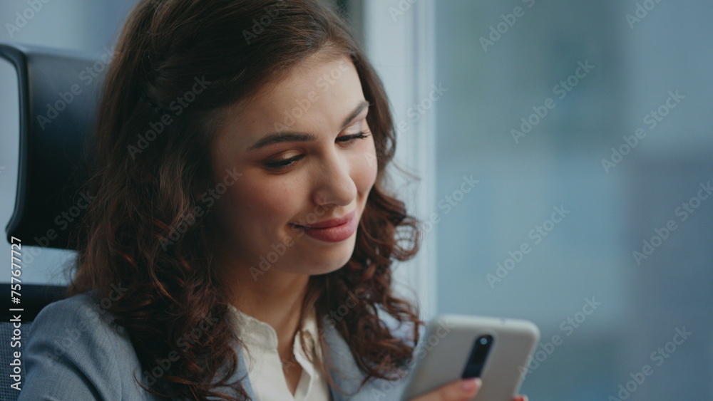 Fototapeta premium Smiling woman receiving message on modern smartphone sitting workplace close up.