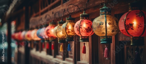 A row of vibrant lanterns adorns the wooden wall at a public event, creating a colorful and artistic display for the entertainment of the crowd