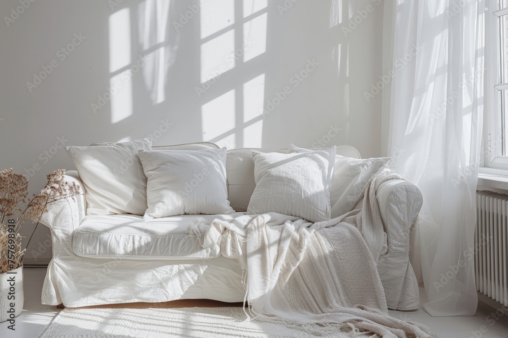 Fototapeta premium A white couch sits in a living room next to a window, filling the space with light and offering a cozy spot to relax