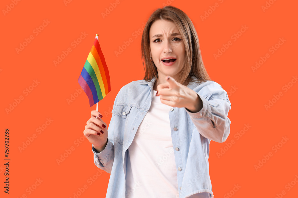 Young woman with LGBT flag pointing at viewer on orange background. Accusation concept Young woman with LGBT flag pointing at viewer on orange background. Accusation concept