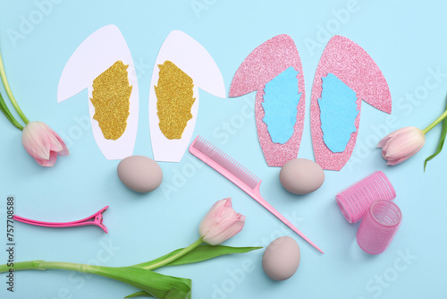 Hairdressing accessories with Easter eggs, paper bunny ears and tulips on blue background