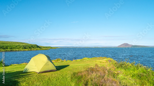 Panorama with a lonely green tent pitched at Myvatn lake shore at sunny day and blue sky with copy space, at central camping site