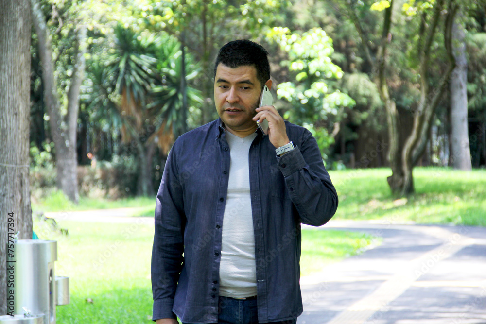40-year-old dark-skinned Latino man walks while using his cell phone to make video calls, send messages, make payments, shop and work remotely 40-year-old dark-skinned Latino man walks while using his cell phone to make video calls, send messages, make payments, shop and work remotely