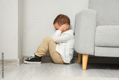 Lonely little boy with autistic disorder sitting on floor at home