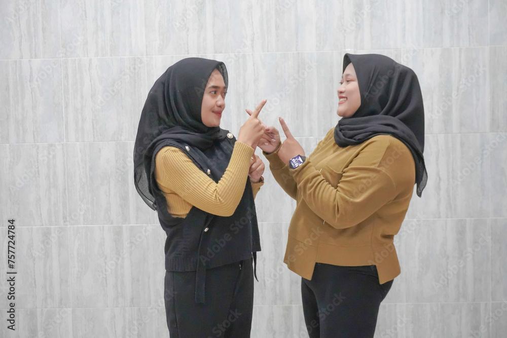 The happy expression of two Asian Indonesian hijab women wearing brown and black clothes