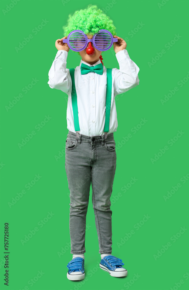 Little boy in funny glasses and clown wig on green background. April Fools Day celebration Little boy in funny glasses and clown wig on green background. April Fools Day celebration