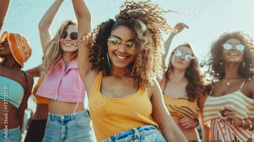 Group of young women in trendy outfits dancing together at a music festival or club