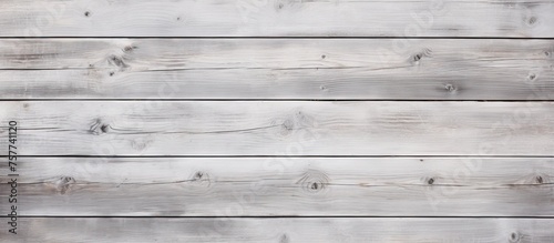 A close up photo of a rectangular grey hardwood plank flooring with a wood stain finish on a white wooden wall. The planks are parallel and create a stunning visual font