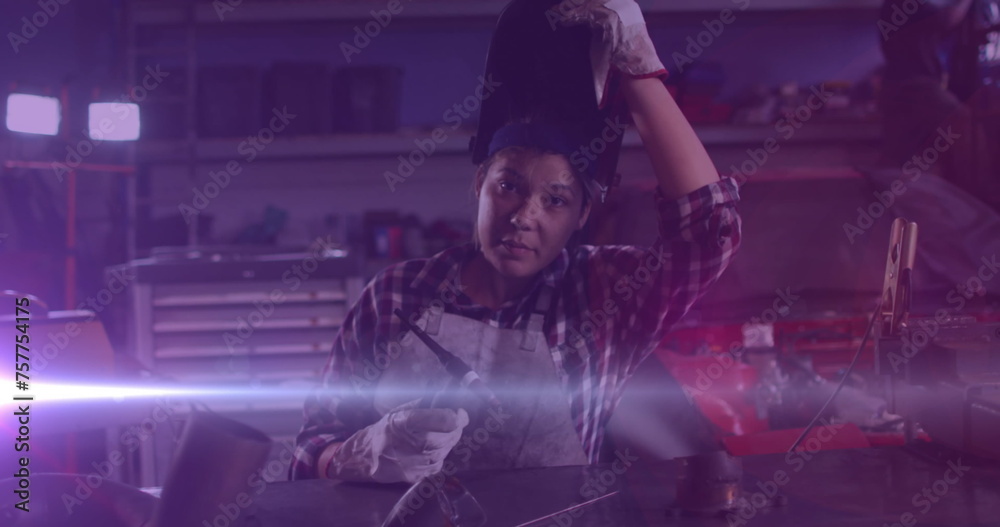 Fototapeta premium Image of glowing light over caucasian woman working in workshop
