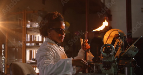 Image of glowing light over african american woman working in workshop