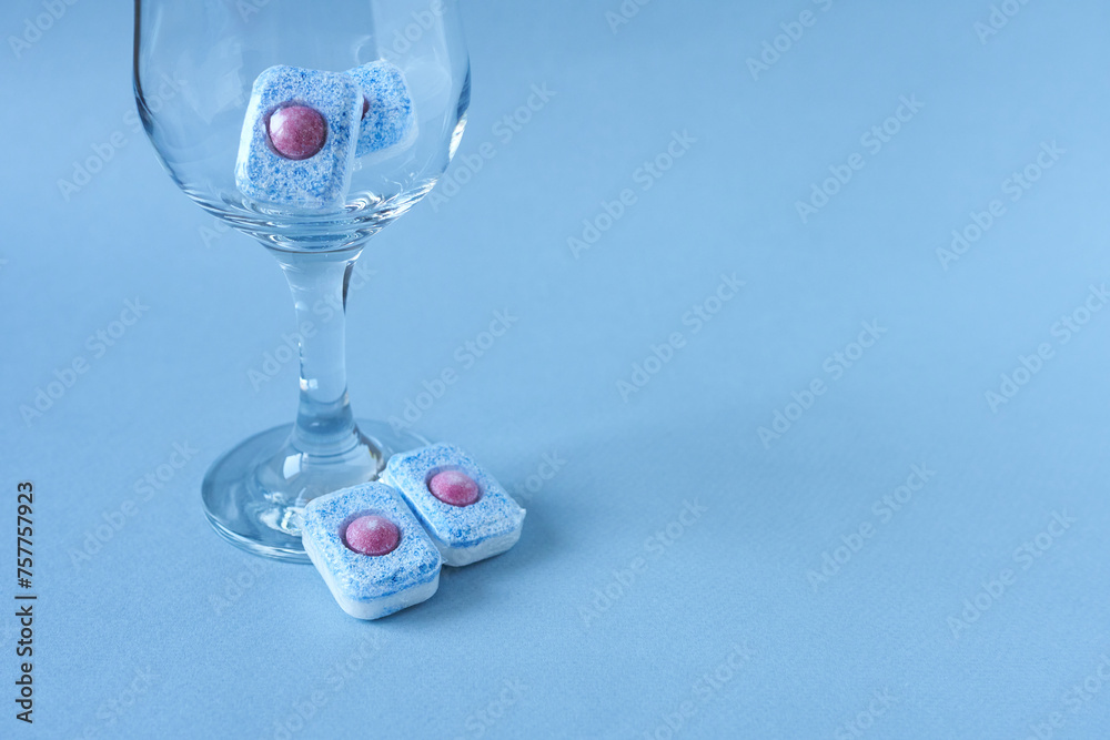 Dishwasher tablets in a glass on a blue background with copy. Dishwasher tablets in a glass on a blue background with copy.