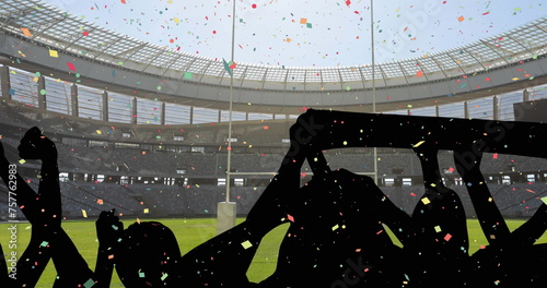 Colorful confetti falling against silhouette of fans cheering and sports stadium in background