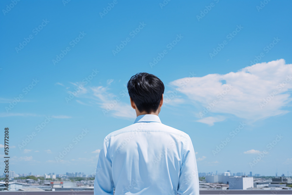 青空にを見上げるアジア人のビジネスパーソン