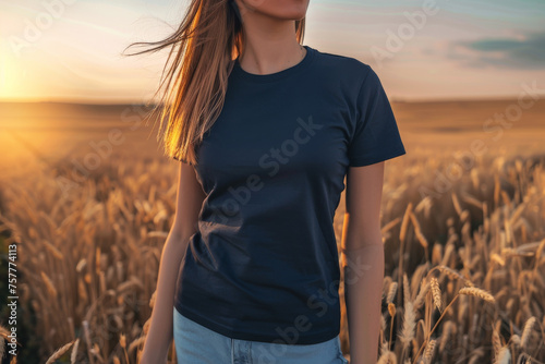 Caucasian female model wearing a navy blue crewneck blank mockup t-shirt with short sleeves in a field background at sunset , woman face is not visible photo