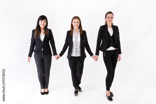 Team of three business women holding hands.