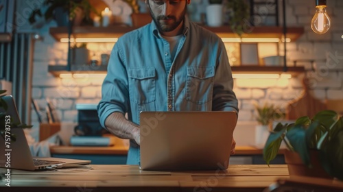 Young man working on laptop computer at home office. Male hands typing on keyboard photo