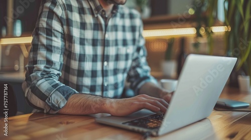 Young man working on laptop computer at home office. Male hands typing on keyboard photo