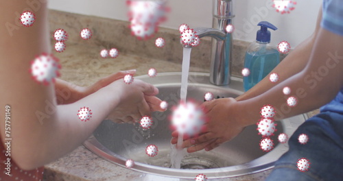Image of coronavirus cells over caucasian mother with son washing hands at home