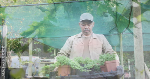 Image of blue lights over biracial man working in the garden