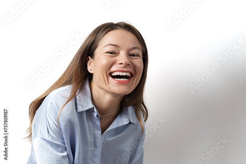 A cheerful woman smiling and laughing against a white background.