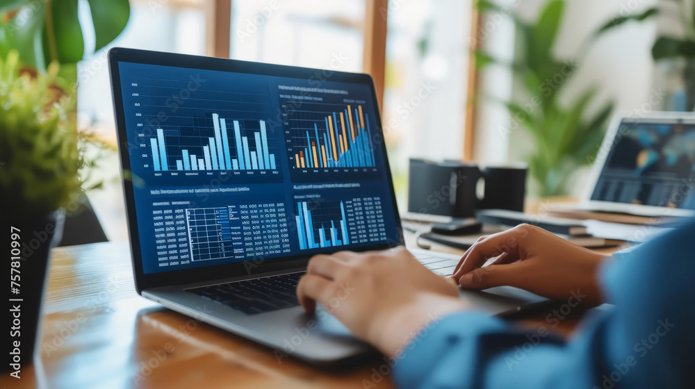 Financial analysts reviewing data charts on laptop in office Financial analysts reviewing data charts on laptop in office
