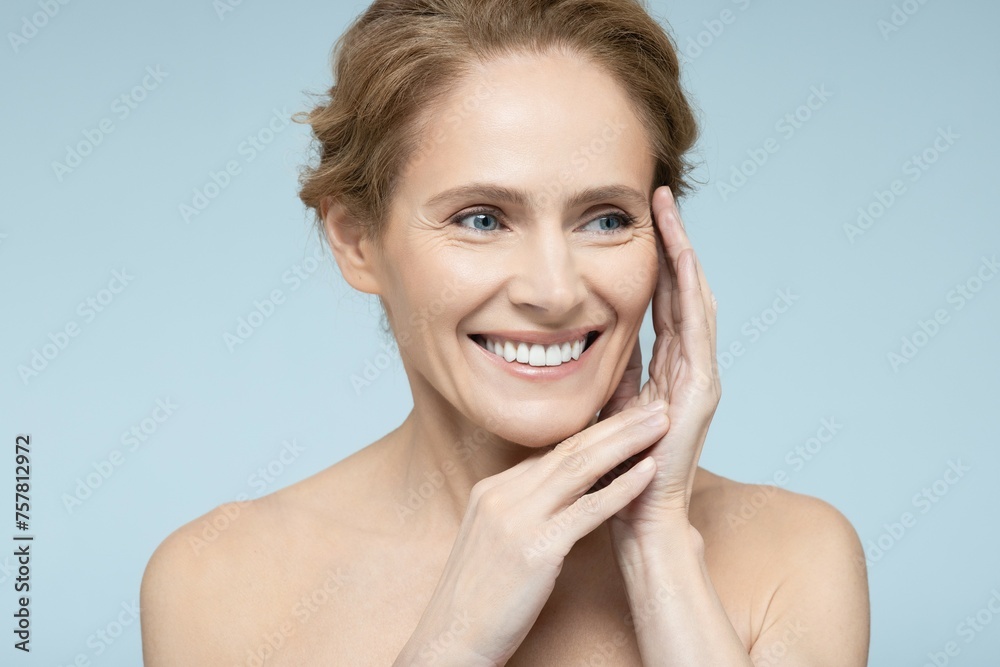 Portrait of a woman in her forties highlighting her smooth complexion and shiny skin against blue setting Portrait of a woman in her forties highlighting her smooth complexion and shiny skin against blue setting