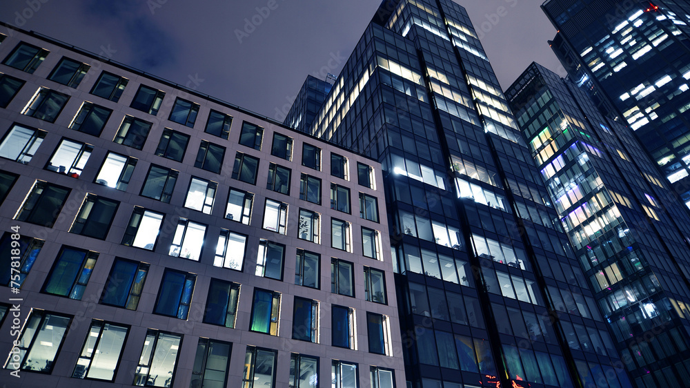 Office building at night, building facade with glass and lights. View with illuminated modern skyscraper. Office building at night, building facade with glass and lights. View with illuminated modern skyscraper.