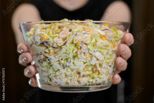 Duża szklana miska wypełniona sałatka z majonezem i kurczakiem trzymana w dłoniach 