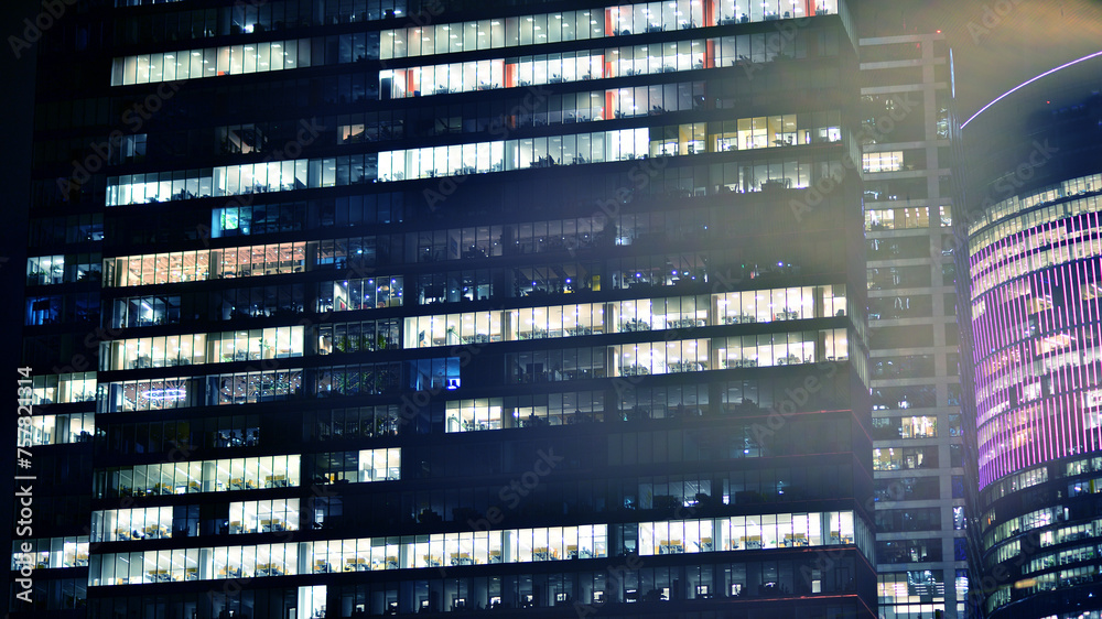 Office building at night, building facade with glass and lights. View with illuminated modern skyscraper. Office building at night, building facade with glass and lights. View with illuminated modern skyscraper.