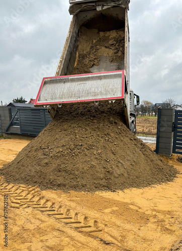 Truck dumping soil during construction at new home