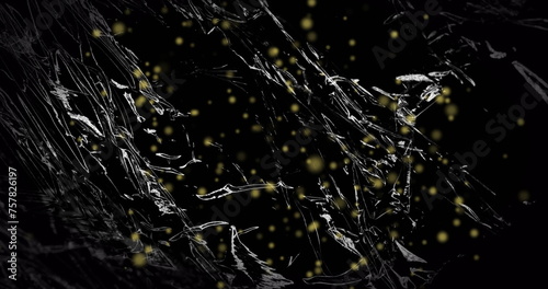 Image of yellow particles floating over light on moving shiny black plastic
