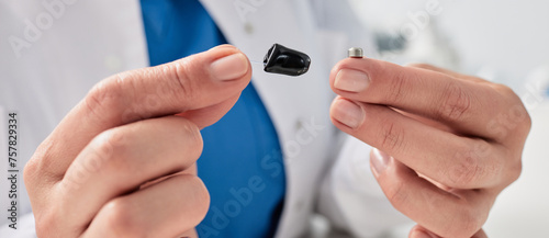 Hearing aid battery replacement. Audiologist showing ITC hearing aid and battery for it, holding them in her hands in front of him
