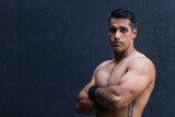 Face of male athlete or personal trainer with strong muscle, power and motivation with arms crossed at black wall