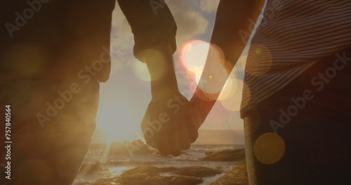 Image of light spots over caucasian couple walking and holding hands