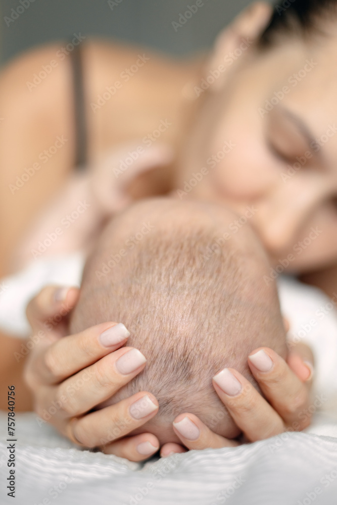 Φωτογραφία happy mother kisses and hugs the baby, hands on the baby's head.