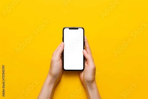A person is holding a cell phone with two hands with a yellow background