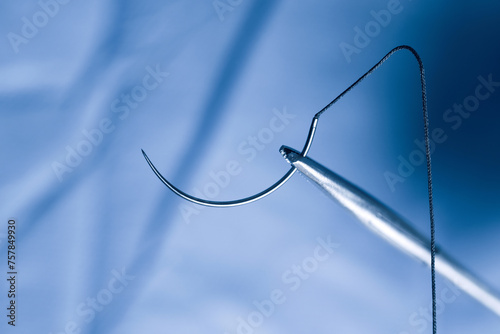 Closeup photo of a needle holder and half circle needle with suture during operation.