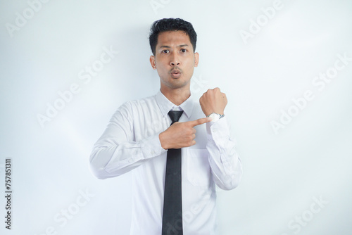Adult Asian man sitting in a chair and showing angry face expression while pointing to his arm watch photo