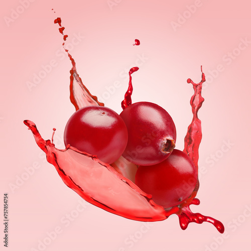 Delicious ripe cranberries and splashing juice in air on pale red background