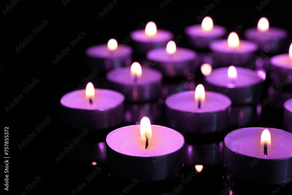 Beautiful burning violet candles on black background. Funeral attributes Beautiful burning violet candles on black background. Funeral attributes