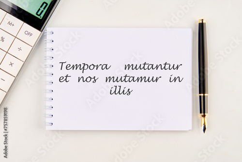 Tempora mutantur et nos mutamur in illis Translated from Latin, it means Times are changing, and we are changing with them. on a white notebook photo