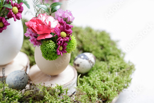 Florist at work: woman shows how to make simple Easter decoration with egg shell and various flowers.