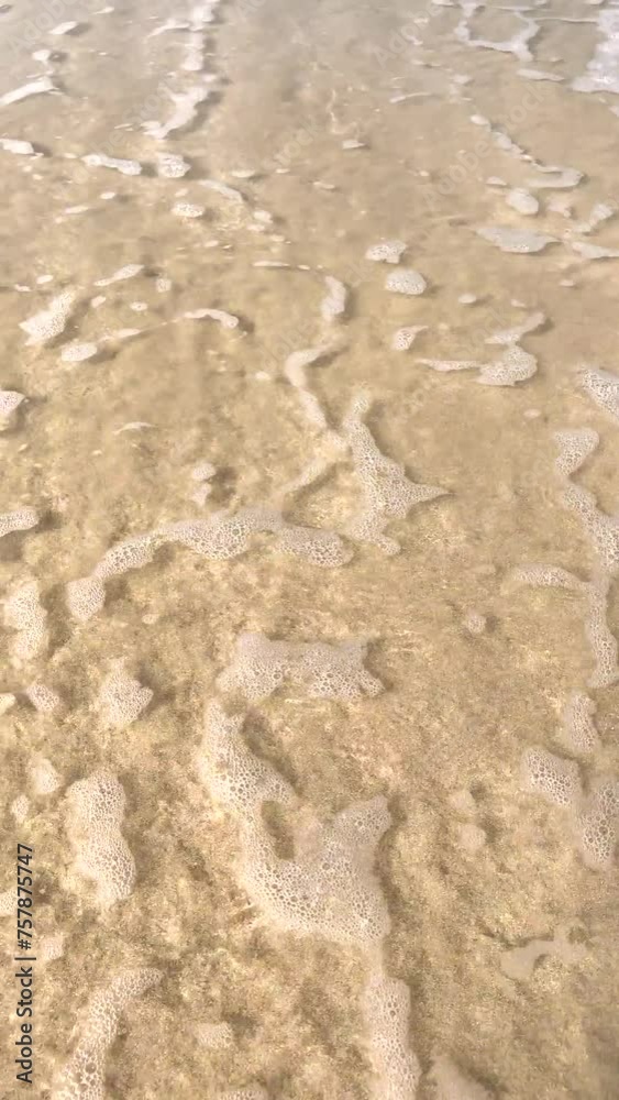 Waves on the sandy shore. View from above. Close-up. The movement of a wave on smooth sea sand. The seashore. Seascape. Waves on the beach. A sunny summer day. Waves on the sandy shore. View from above. Close-up. The movement of a wave on smooth sea sand. The seashore. Seascape. Waves on the beach. A sunny summer day.