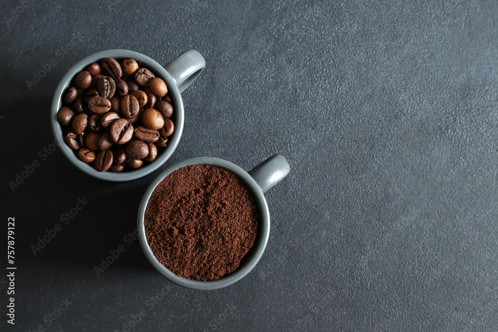 Fototapeta premium Due tazze di caffè grigie con chicchi di caffè e caffè macinato isolati su sfondo grigio. Vista dall'alto. Copia spazio.