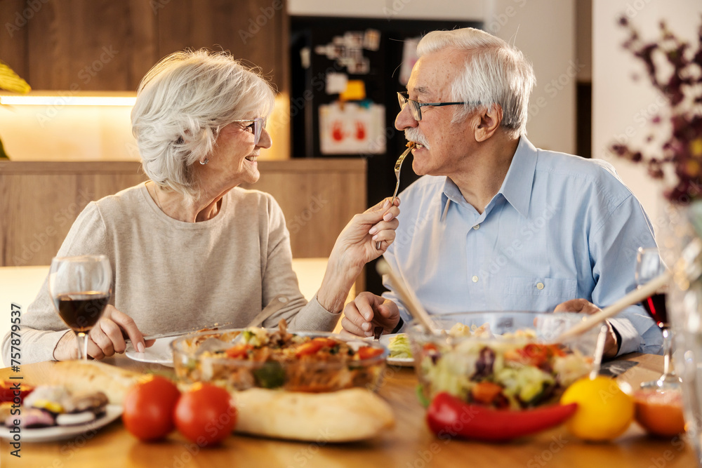 A senior woman is feeding her husband at lunch table at home. A senior woman is feeding her husband at lunch table at home.