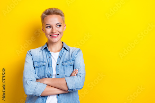 Photo portrait of attractive young woman folded arms look empty space dressed stylish denim clothes isolated on yellow color background © deagreez