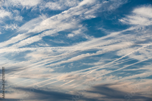 Viele, sich teilweise kreuzende Kondensstreifen am blauen Himmel mit aufgelockerter Bewölkung und Cirruswolken