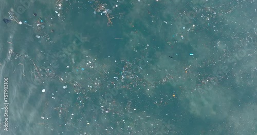 Top down descending drone shot over polluted water filled with plastic trash in the turqouise tropical water of Balangan Beach Uluwatu Bali Indonesia photo